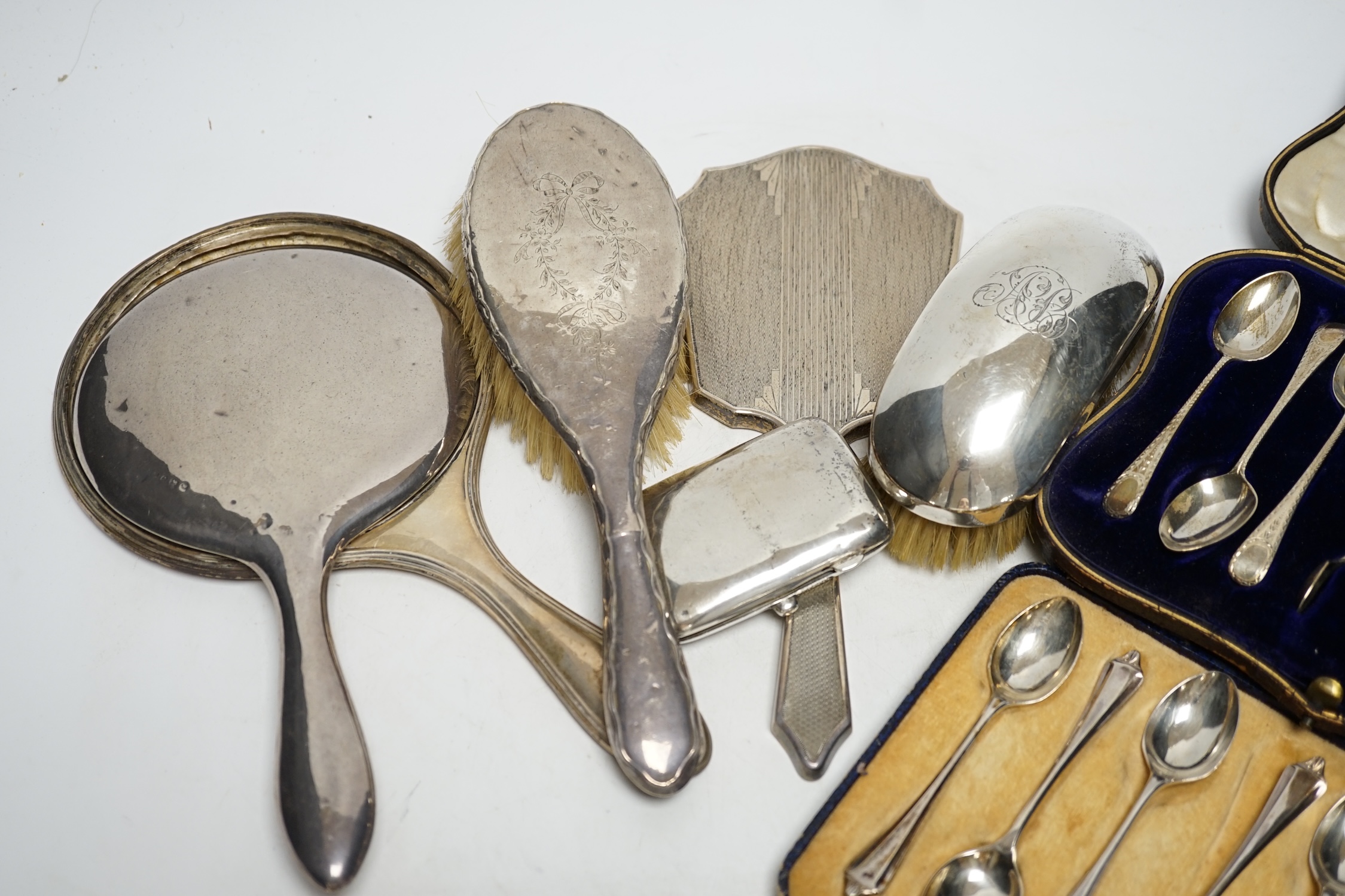 Two cased sets of six silver teaspoons, assorted silver mounted brushes and damaged mirror and a silver cigarette case.